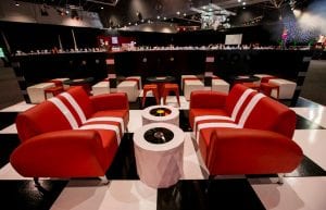 black and white chequered dance floor and diner booth with retro sofas with white stripes. White tables with record tops.