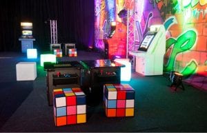 graffiti themed backdrop with old fashioned arcade games and light up furniture and rubix cube designed seats