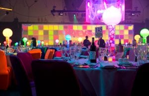 Room shot at Perth Convention Centre pavilion for gala dinner showing 1980s themed table centrepieces and av screen with rubix cube design