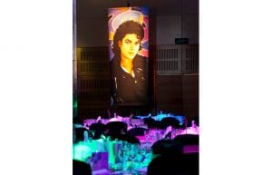 illuminated prop of michael jackson, lit from behind. Dinner tables of 10 with eighties themed table cetrepieces