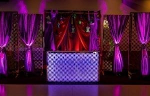 arabian nights aladdin themed dj booth illuminated in purple with backdrop of coloured silks and hanging arabian lanterns