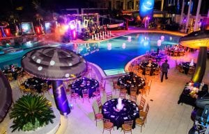aerial view of alice in wonderland themed dinner poolside at crown perth. giant 4m inflatable mushrooms, table settings and floating lights in pool