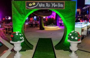 mad hatter entry archway for event with curved section for guests to enter down the rabbit hole. we're all mad here sign on top