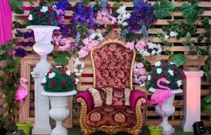 pallet wall covered in flowers. red and gold throne. large standing flamingo props. topiary balls in urns iwth red and white roses alice in wonderland theme