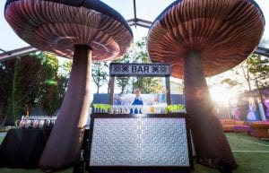 huge inlfatable 4m mushrooms on either side of a silver pressed tin bar with overhead sign alice in wonderland theme