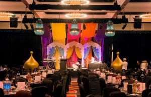 arabian nights themed gala dinner at crown perth. stage set with bollywood arches and coloured silk drapes from the ceiling. large gold domes either side of stage