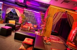 arabian nights themed cocktail event, low wooden tables for chill out area with black bench seats and arabian cushions and rugs and arabian themed chill out cabana hut