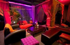 arabian nights themed cocktail event, low wooden tables for chill out area with black bench seats and arabian cushions and rugs and arabian themed chill out cabana hut
