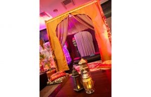 arabian nights themed cocktail event, low wooden tables for chill out area with black bench seats and arabian cushions and rugs and arabian themed chill out cabana hut