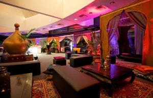arabian nights themed cocktail event, low wooden tables for chill out area with black bench seats and arabian cushions and rugs and arabian themed chill out cabana hut