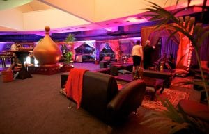 arabian nights themed cocktail event, low wooden tables for chill out area with black bench seats and arabian cushions and rugs and arabian themed chill out cabana hut, gold dome and sofas