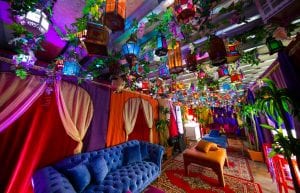 arabian nights themed cocktail event with hundreds of hanging lanterns and vines from roof. silk arabian archway backdrops and blue velvet sofas with arabian rugs