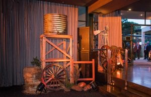 australiana outback themed event with water tank on stand, hay bales, wagon wheel, windmill and fake rocks