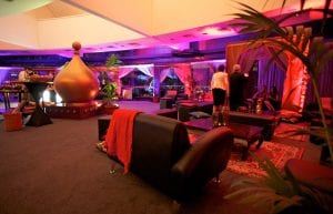 arabian nights theming chill out tent with silk drapes low wooden table persian rug and lanterns. gold dome set pieces palm trees