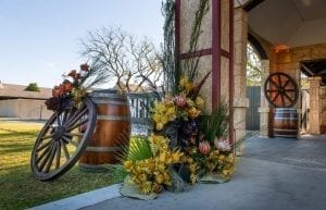Wild West modern event styling theme with entry feature, native florals, wagon wheels, wine barrels, parcan light prop for hire. Photo taken at Camfield Perth for corporate conference
