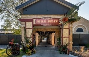 Wild West modern event styling theme with entry feature, native florals, wagon wheels, wine barrels, parcan light prop for hire.