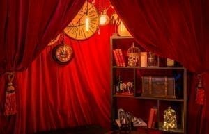 Steam Punk event theme with red drapes, Edison globe lights, bookcase, trunk, skull, birdcages, clocks and styling items for hire