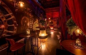 Steam Punk event theme with red drapes, large gold frames, steam punk prints, crystal beaded chandeliers, steam punk backdrop, lanterns, velvet sofas, cushions, cow print rugs, birdcages, coffee tables, Edison globes, greenery, gobos, cloche dome centrepieces, trussing, hi bar takes and stools for hire.