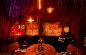 Steam Punk event theme with red drapes, large gold frames, steam punk prints, crystal beaded chandeliers, lanterns, velvet sofas, cushions, cow print rugs, birdcages, coffee tables, Edison globes, greenery, gobos, cloche dome centrepieces, fiddle leaf fig plants, trussing, hi bar takes and stools for hire.