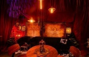 Steam Punk event theme with red drapes, large gold frames, steam punk prints, crystal beaded chandeliers, lanterns, velvet sofas, cushions, cow print rugs, birdcages, coffee tables, Edison globes, greenery, gobos, cloche dome centrepieces, fiddle leaf fig plants, trussing, hi bar takes and stools for hire.