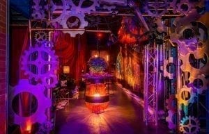 Steam Punk event theme with red drapes, large gold frames, steam punk prints, crystal beaded chandeliers, lanterns, velvet sofas, cushions, cow print rugs, birdcages, coffee tables, steam punk backdrop, , gobos, cloche dome centrepieces, trussing, hi bar takes and stools for hire