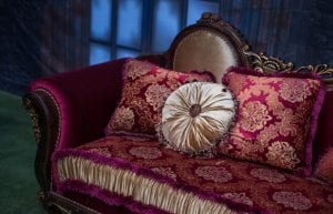 Rocky Horror event theme with gothic window drape backdrop, red and gold velvet sofa and cushions for hire.