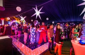 Space event theme with black drapes, led dance floor, star cloth, giant inflatable stars, curved trussing entry feature, illuminated led hi bar furniture, lycra hi bar covers, coloured ghost stools, tiered orb centrepieces and wicker ball lights for hire.