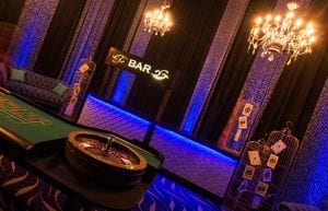 Las Vegas event styling theme with, pressed tin light up bar, velvet sofas, birdcages, playing cards, centrepieces, chandeliers, cushions, hi bar tales, stools, casino tables, beaded curtains for hire. Photo taken at Crown Perth for Christmas Party.