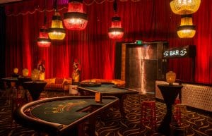 Las Vegas event styling theme with, pressed tin light up bar, velvet sofas, birdcages, lanterns, playing cards, centrepieces, colour beaded chandeliers, cushions, hi bar tales, stools, casino tables, red drapers, illuminated 007 bond props and beaded curtains for hire. Photo taken in Perth for Christmas Party.