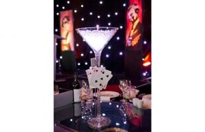 Las Vegas event styling theme with, playing cards, martini glass centrepieces, colour beaded hi bar tales, stools, illuminated 007 bond props and star cloth backdrop for hire. Photo taken in Perth for Christmas Party.
